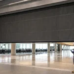 Engineers inspecting a partially deployed active fire curtain in a public lobby